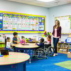 The image depicts a bright and welcoming classroom at Franklin Academy filled with colorful educational posters and resources tailored for students with disabilities Desks are arranged in small groups to encourage collaboration while a large whiteboa-1